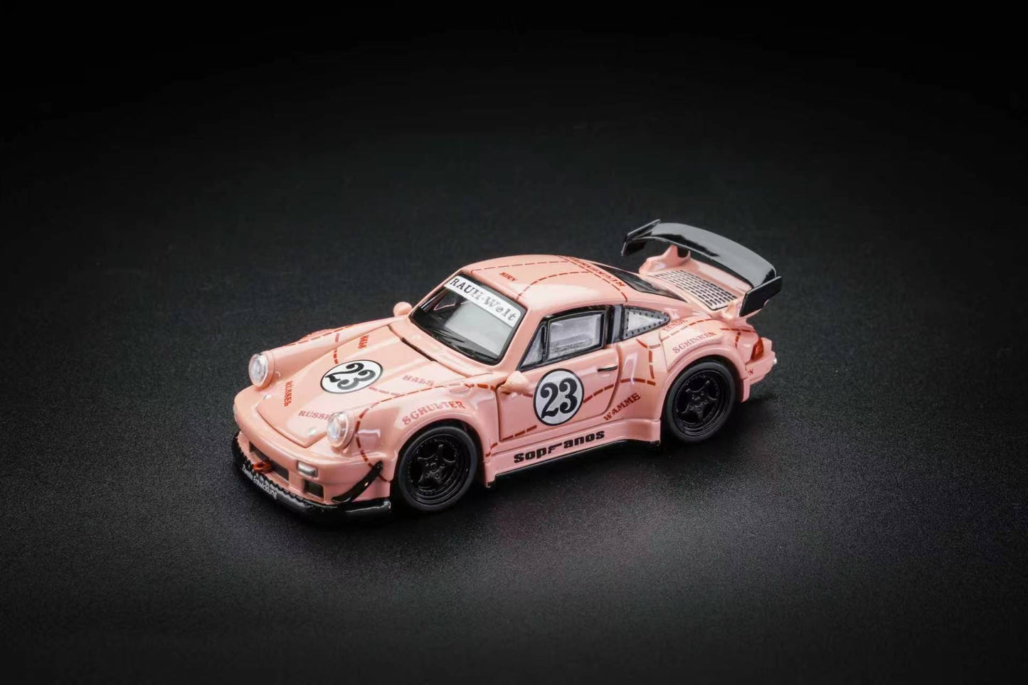 A pink and white patterned diecast model car resembling a Porsche 911 race car, featuring the number 23 and 'SODAPUNK' branding, set against a dark textured background.