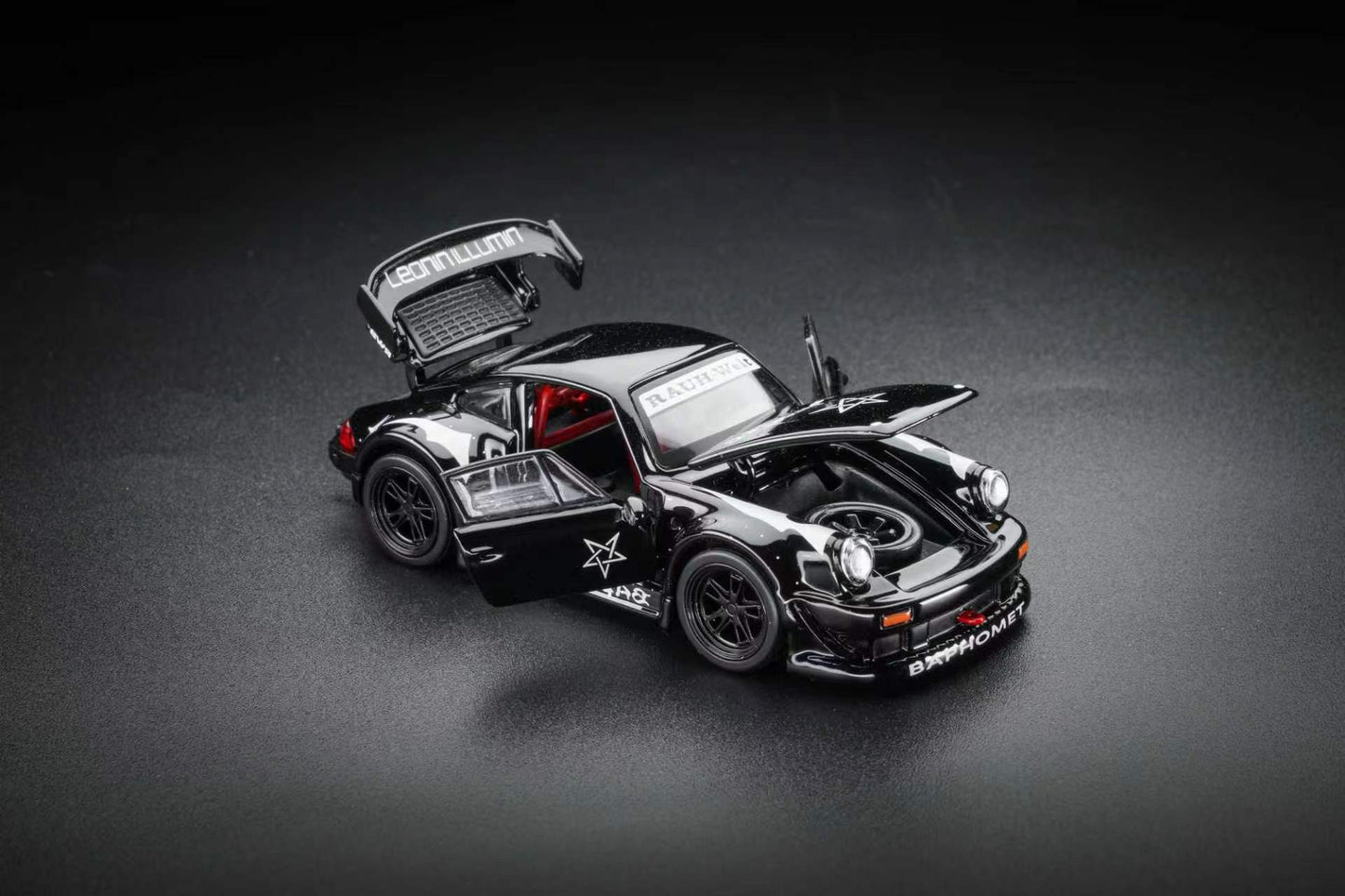 A black die-cast model car with its doors and trunk open, displayed on a dark gray studio background. The car features white text decals, including 'MUTUAL' on the trunk lid and 'DISCIPLINED' on the front bumper, along with a white star graphic on the side.