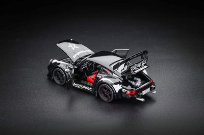 A scale model of a black and silver Porsche 911 race car with its doors and trunk open, showcasing a red interior and detailed engine, set against a dark studio background.