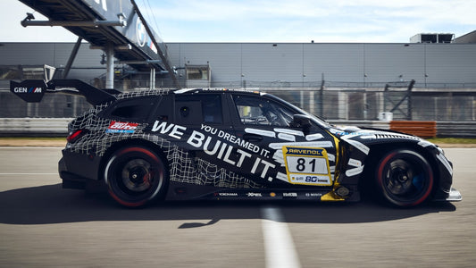 MINICHAMPS 1:64 BMW M3 Touring 24H April Fools Day Inception Design 2025 diecast model race car in BMW M Motorsport camouflage livery, left side profile view on racetrack, featuring widebody aerodynamic kit, large rear wing, racing wheels and detailed GT endurance racing design.