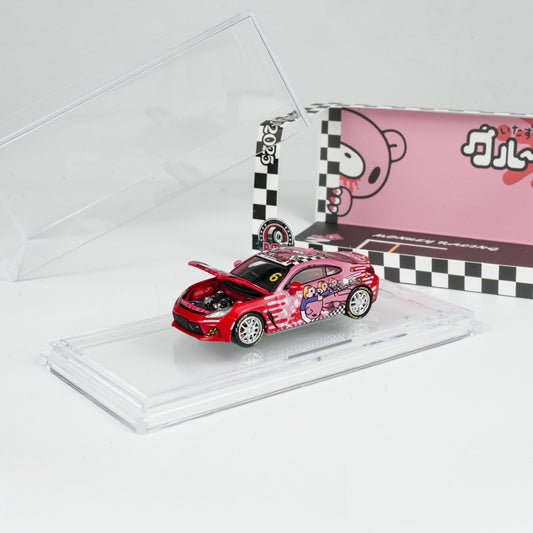 A red toy car with anime-themed graphics displayed in a clear case. The box features a checkered design and cartoon characters, conveying a fun, playful tone.