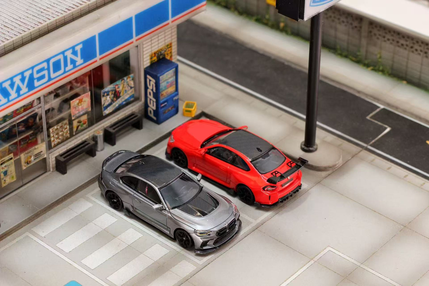 Model cars on a miniature street with a store in the background