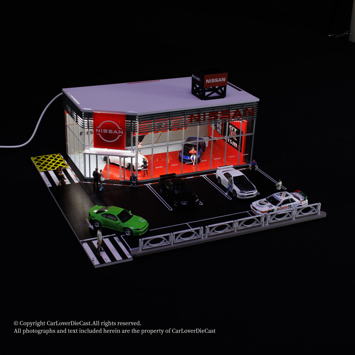 Model of a Nissan car dealership with cars and people on a black background