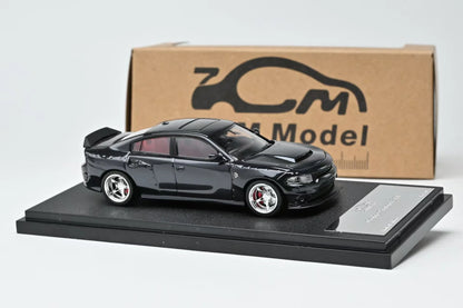 Black model car on a display stand with a branded box in the background
