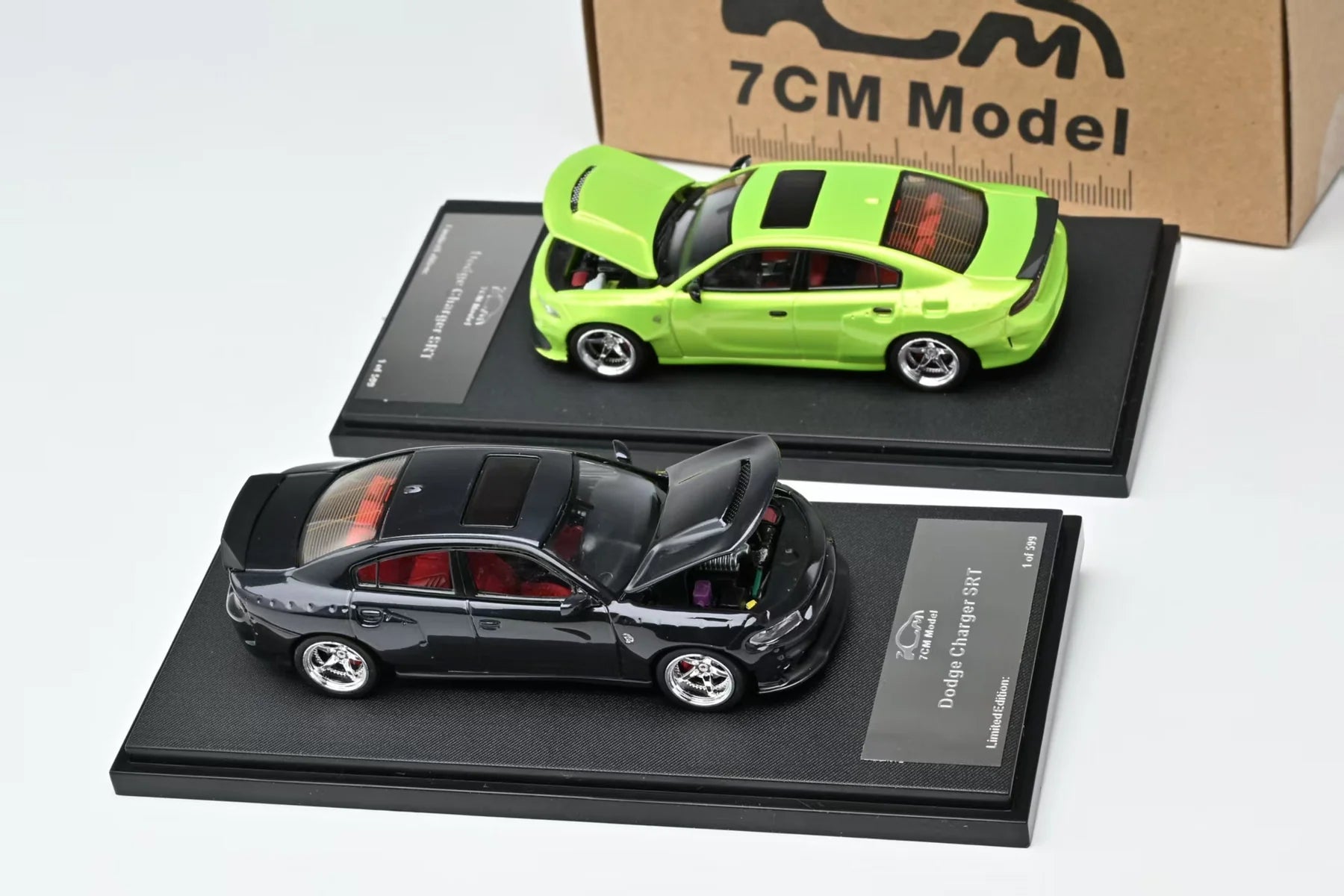 Two model cars on display stands with a cardboard box labeled '7CM Model' in the background.