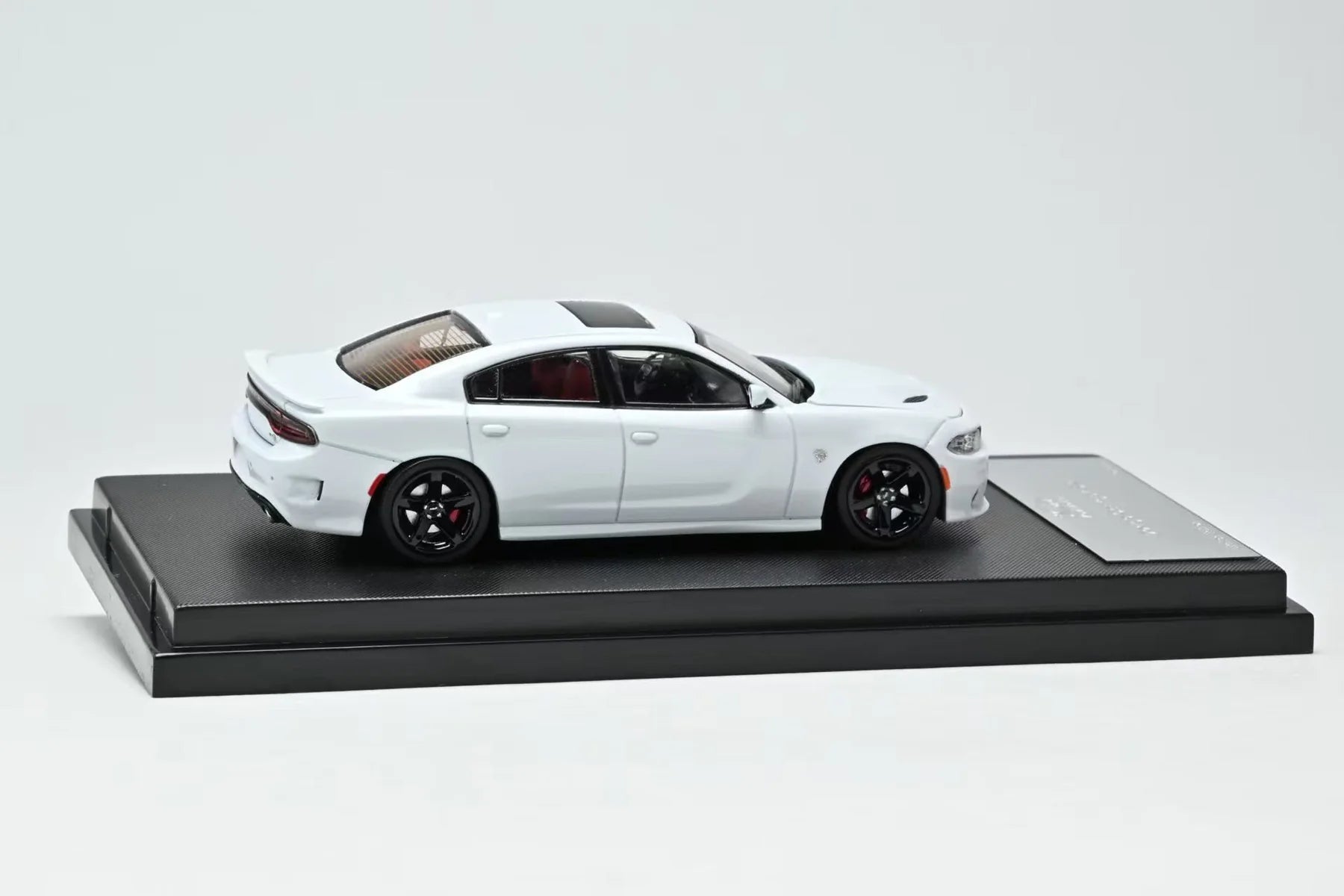 White model car on a black platform with a gray background