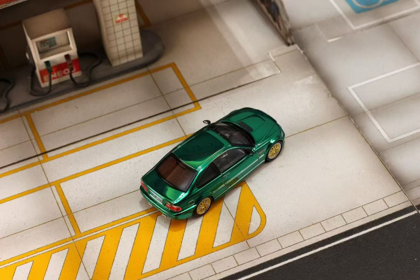 Model car on a miniature road with a gas station in the background