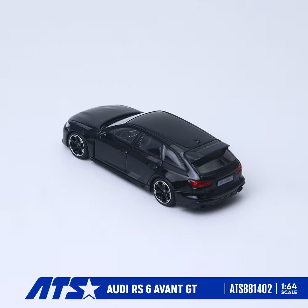 A black 1:64 scale diecast model car of an Audi RS 6 Avant GT, shown from a three-quarters rear angle on a light gray background with a blue brand banner at the bottom.
