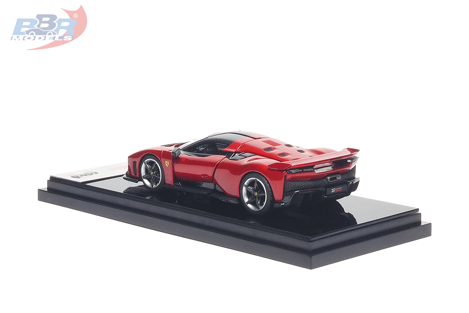 1:64 scale Ferrari F80 diecast model in Rosso Corsa red displayed on a premium black presentation base, shown from the rear three-quarter angle. Features carbon fiber accents, sculpted aerodynamic bodywork, realistic alloy wheels, detailed rear diffuser and taillights, making it a premium collectible for Ferrari enthusiasts and diecast model collectors