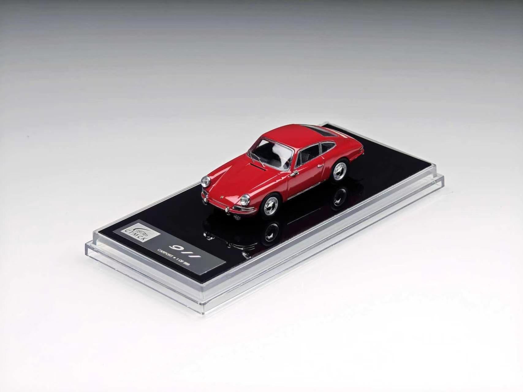 A red miniature model car displayed on a black base inside a clear acrylic case, photographed on a clean light gray studio background.