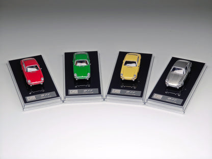 Four miniature model cars in red, green, yellow, and silver, each mounted on a black display card with a clear plastic case, arranged in a row on a light gray background.