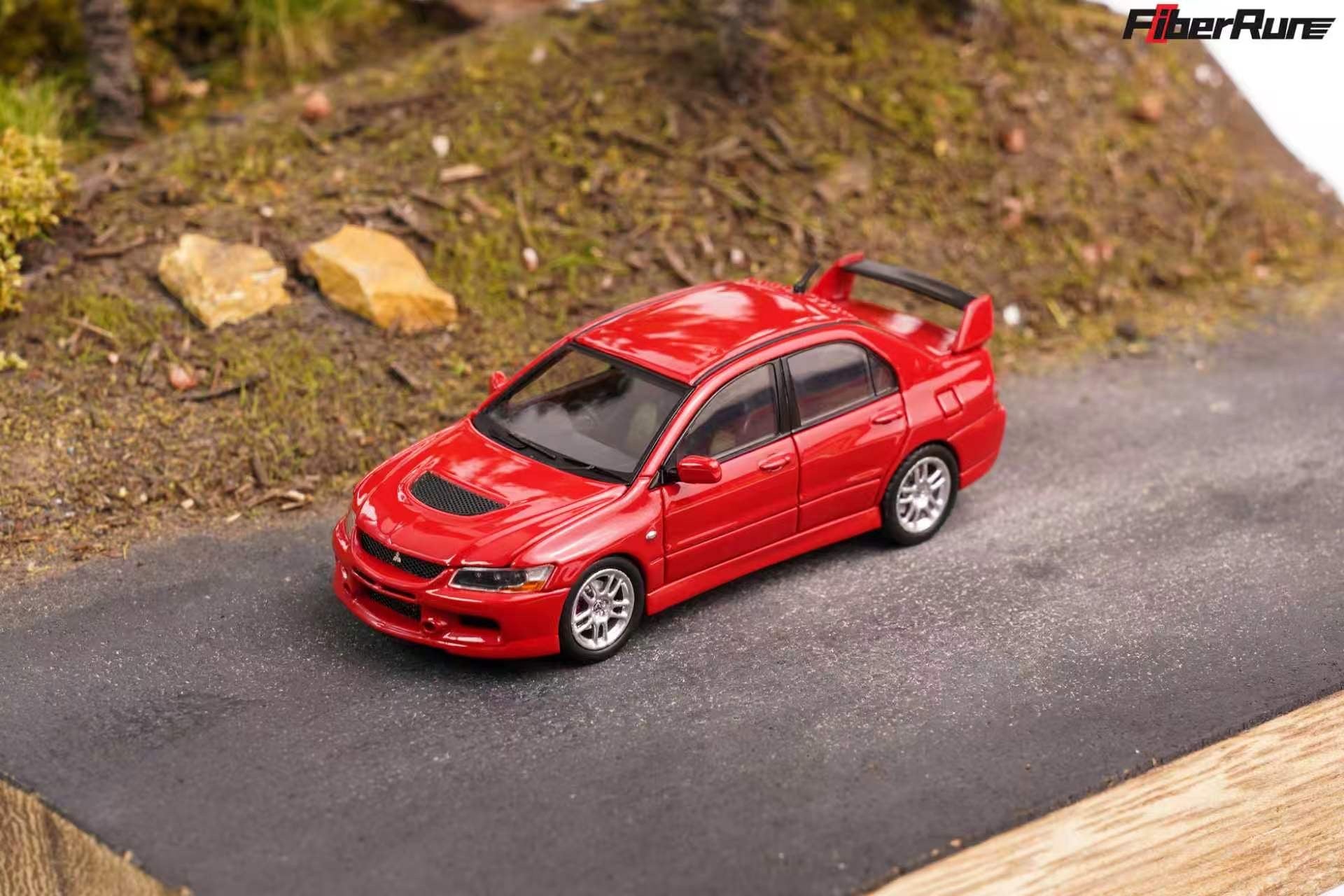 A red die-cast model car resembling a Subaru Impreza WRX, shown on a miniature asphalt road with a diorama background of grass and rocks. The FiberRun brand logo is visible in the top right corner.