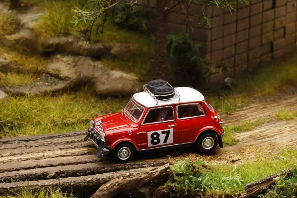 Model car with number 87 on a miniature landscape with rocks and grass.
