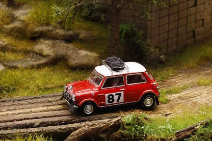 Model car with number 87 on a miniature landscape with rocks and grass.