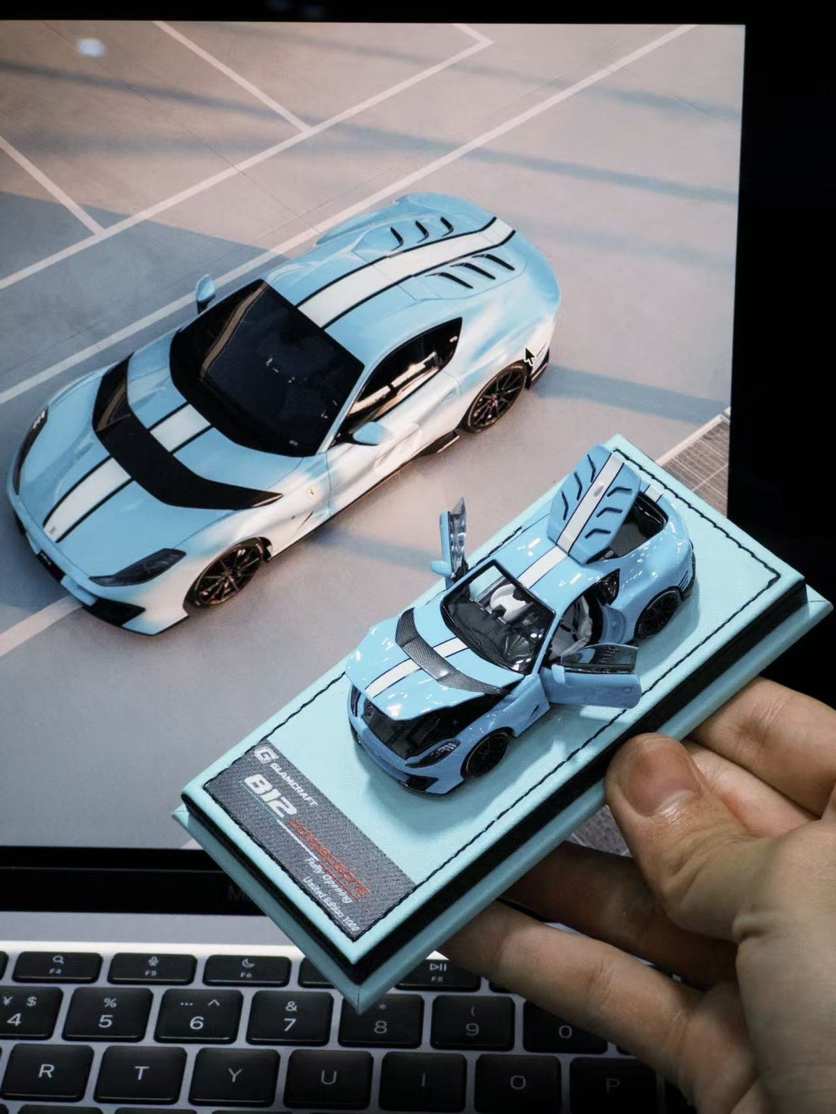 GLAMCRAFT 1:64 Ferrari 812 Competizione Light Blue with White Stripes diecast model car with opening parts displayed beside full-size Ferrari 812 Competizione