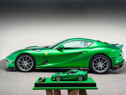 Green Ferrari sports car and a smaller model car on a gray background