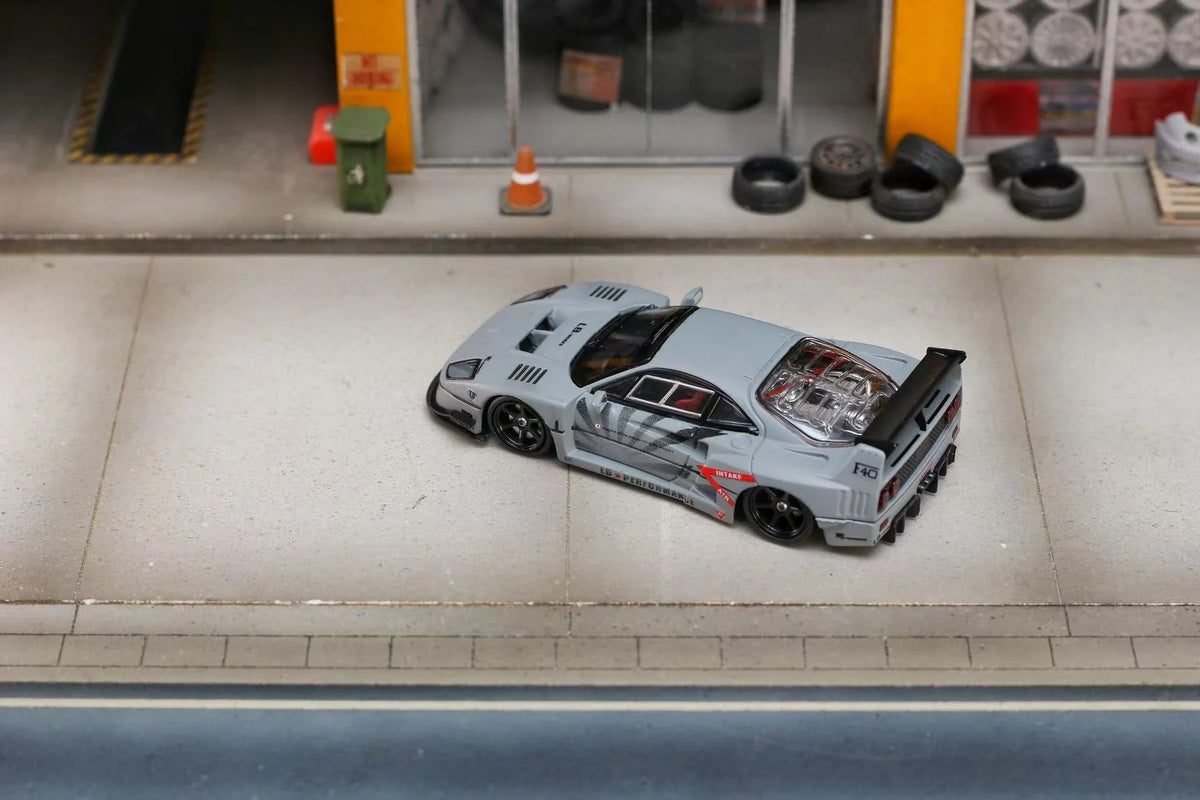 Model car on a tiled floor with tires and a small building in the background