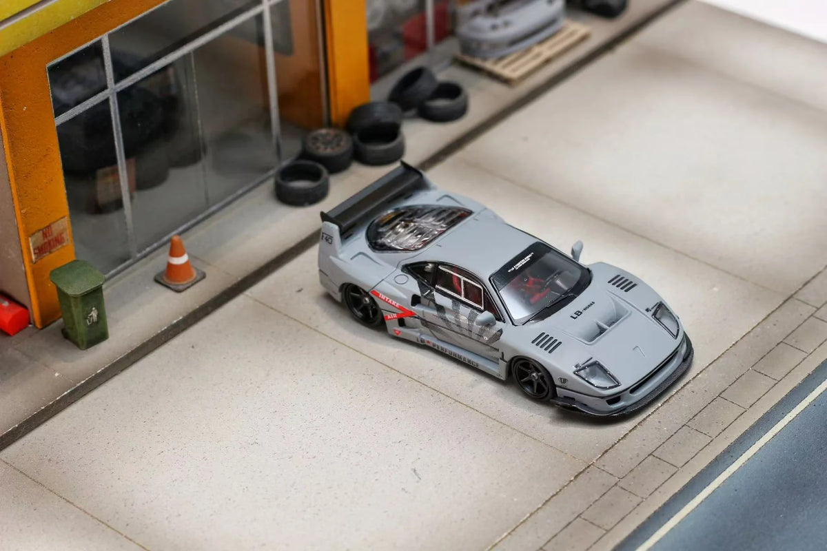 Model car on a miniature street setup with buildings and traffic cones.