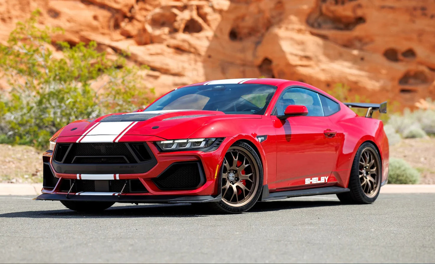 A red 2025 Shelby Mustang Supersnake race model car in a desert setting.