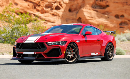 A red 2025 Shelby Mustang Supersnake race model car in a desert setting.