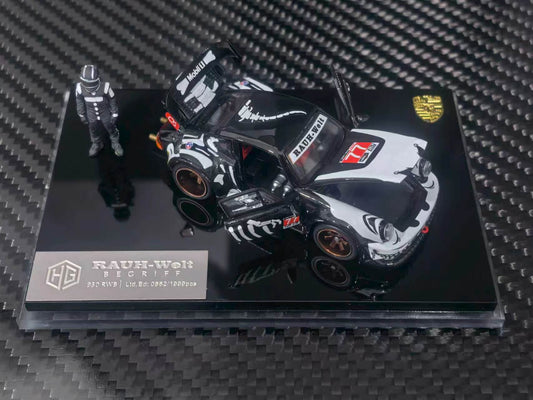 A 1:64 scale model car of a black and white Porsche 911 RSR race car, displayed on a black acrylic base with a small driver figurine. The model is branded by RAUH-Welt and features Porsche branding.