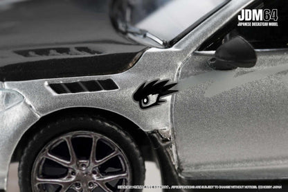 Close-up of a silver diecast car model with black details and stylized eye decal. The text "JDM64 Japanese Diecast Car Model" is in the corner.