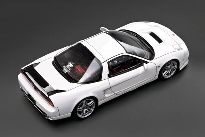 A white diecast model of a sports car, shown from a high-angle perspective on a dark gray background.
