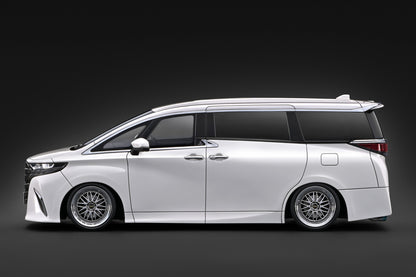 A white customized Toyota Alphard van with a lowered suspension, custom multi-spoke wheels, and a rear spoiler, shown in a side profile against a dark studio background.
