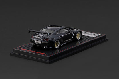 A black die-cast model of a Nissan GT-R Nismo race car, displayed on a black textured base with a small silver plaque, set against a dark gray background.