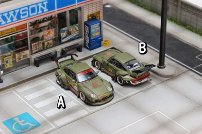Model cars on a miniature street with a store and handicap sign in the background