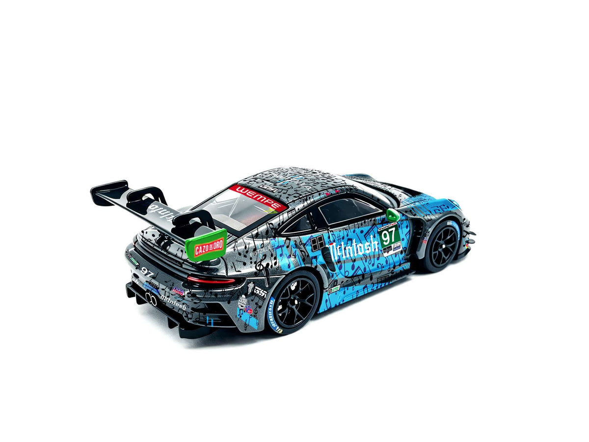 JICAR 1:64 911 GT3 R #97 Blue & Black Music Note Livery diecast model featuring musical note graphics, green side mirrors, black racing wheels, large rear wing and detailed rear diffuser, rear three-quarter view.