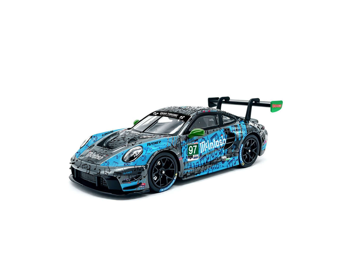 JICAR 1:64 Porsche 911 GT3 R #97 Turner Motorsport Multitask blue and black racing diecast model featuring musical note livery, green side mirrors, black racing wheels and large rear wing, front three-quarter view.