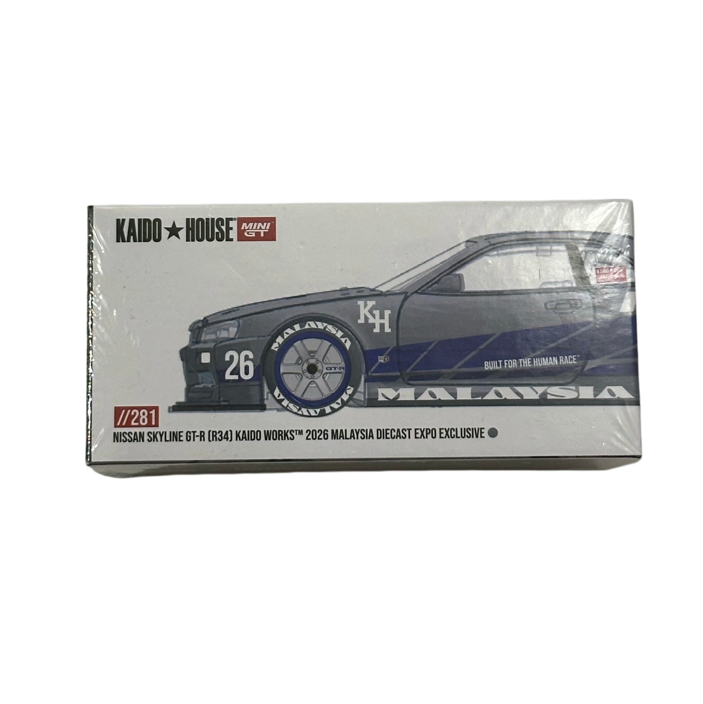 Kaido House Koshō Works 1/64 scale diecast model car packaging for the 2026 Malaysia Nissan Skyline GT-R (R34) exclusive, featuring a blue and white race car illustration on a white box.