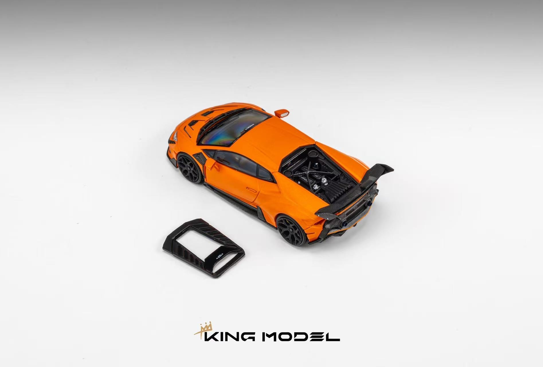 An orange diecast model sports car with a black rear wing and black trim, shown on a light gray gradient background with a small black accessory piece and the KING MODEL logo at the bottom.