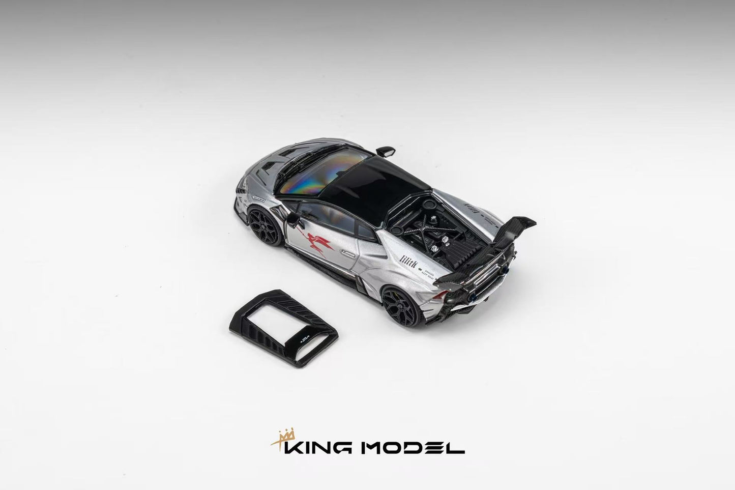 A silver and black diecast model of a sports car with its rear hatch open, shown on a light gray gradient background with a small black accessory piece and the KING MODEL logo at the bottom.