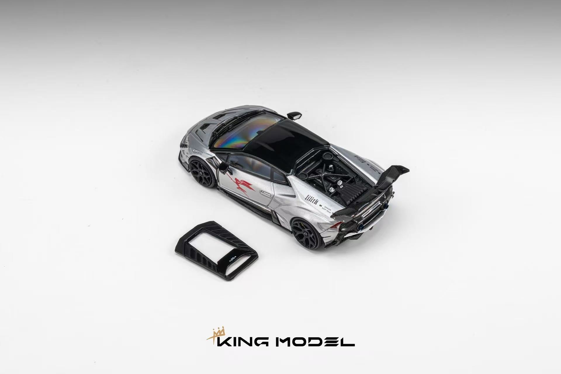 A silver and black diecast model of a sports car with its rear hatch open, shown on a light gray gradient background with a small black accessory piece and the KING MODEL logo at the bottom.