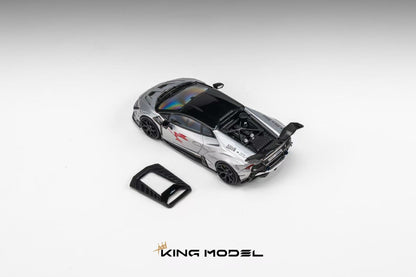 A silver and black diecast model of a sports car with its rear hatch open, shown on a light gray gradient background with a small black accessory piece and the KING MODEL logo at the bottom.