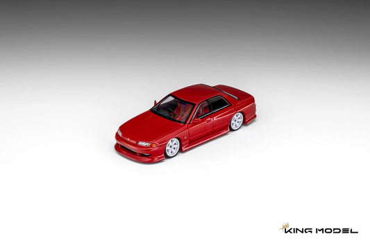 King Model 1:64 Nissan Skyline R32 GTS sedan in metallic red featuring a lowered stance, factory-style body kit, white five-spoke wheels, red interior, and black window trim. Premium diecast model shown in a front three-quarter view on a clean studio background.