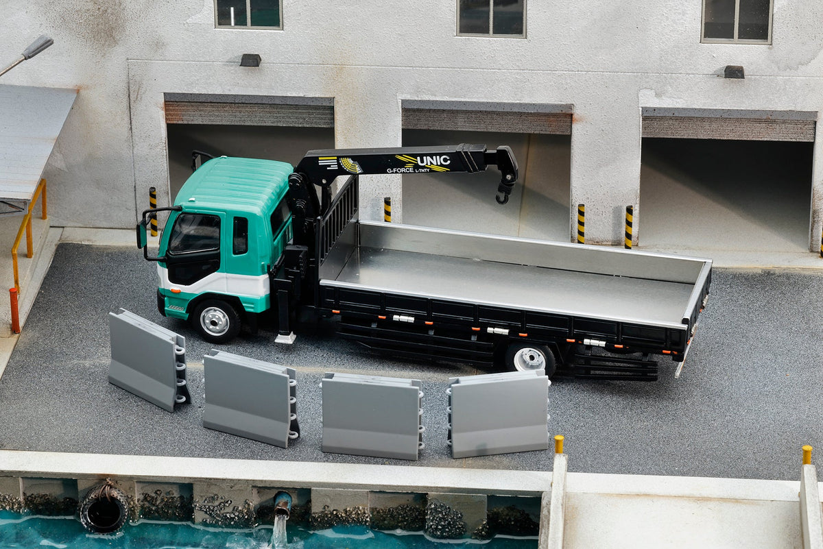 GCD 1:64 Mitsubishi Fuso Fighter (1024) Flatbed Truck with UNIC Crane Green and White No.633 KS-082-633 diecast model, featuring a turquoise green and white cab, black flatbed with silver cargo bed, extended UNIC hydraulic crane with hook, four removable grey cargo panels, and detailed industrial warehouse loading dock diorama.