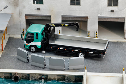 GCD 1:64 Mitsubishi Fuso Fighter (1024) Flatbed Truck with UNIC Crane Green and White No.633 KS-082-633 diecast model, featuring a turquoise green and white cab, black flatbed with silver cargo bed, extended UNIC hydraulic crane with hook, four removable grey cargo panels, and detailed industrial warehouse loading dock diorama.