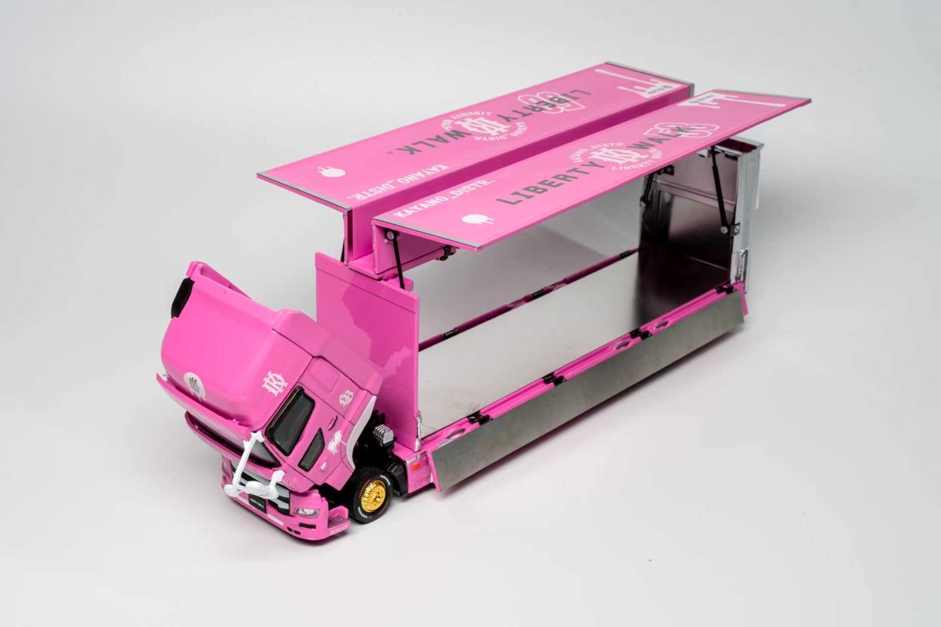 A pink toy model of a semi-truck with an open cargo container, featuring 'Liberty Wink' branding on the side and roof, photographed on a light gray studio background.