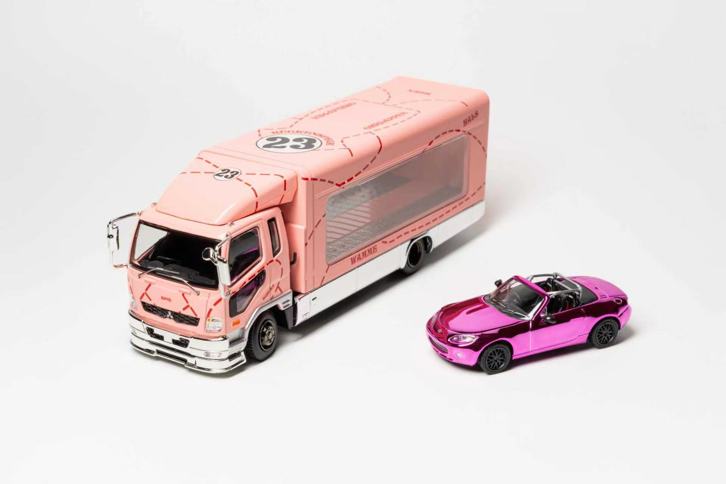 A pink and white toy box truck with a transparent cargo area is shown beside a small metallic pink convertible car on a clean white studio background.