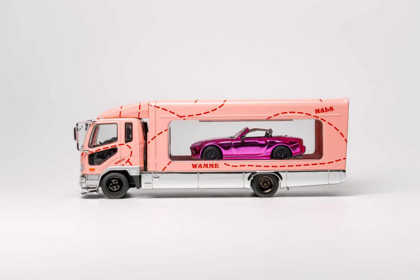 A pink toy truck carrying a purple convertible car in a clear side window, photographed on a clean light gray studio background.