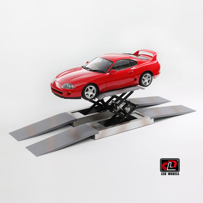 Red car on a scale model lift against a white background