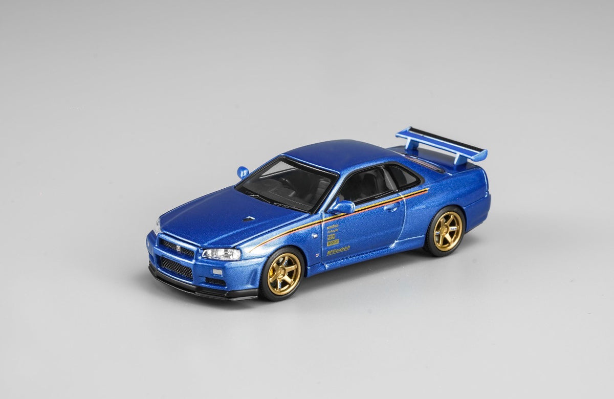 MotorHelix Nissan Skyline GT-R R34 1:64 diecast model in metallic blue, Hong Kong Toycar Salon 2026 exclusive M63453DZ-PT, front three-quarter view with gold wheels, side graphics and rear wing.
