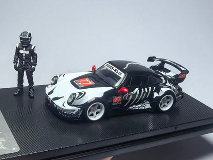 A detailed model of a black race car with white skeletal graphics, featuring "RAUH-Welt" on the windshield. A matching figure in a racing suit stands beside it.