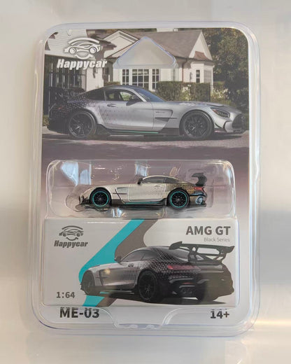 A Happycar 1:64 scale diecast model car of a Mercedes-AMG GT Black Series, packaged in a clear plastic blister pack with its original card backing. The model car features a black and white carbon-fiber pattern with teal accents.