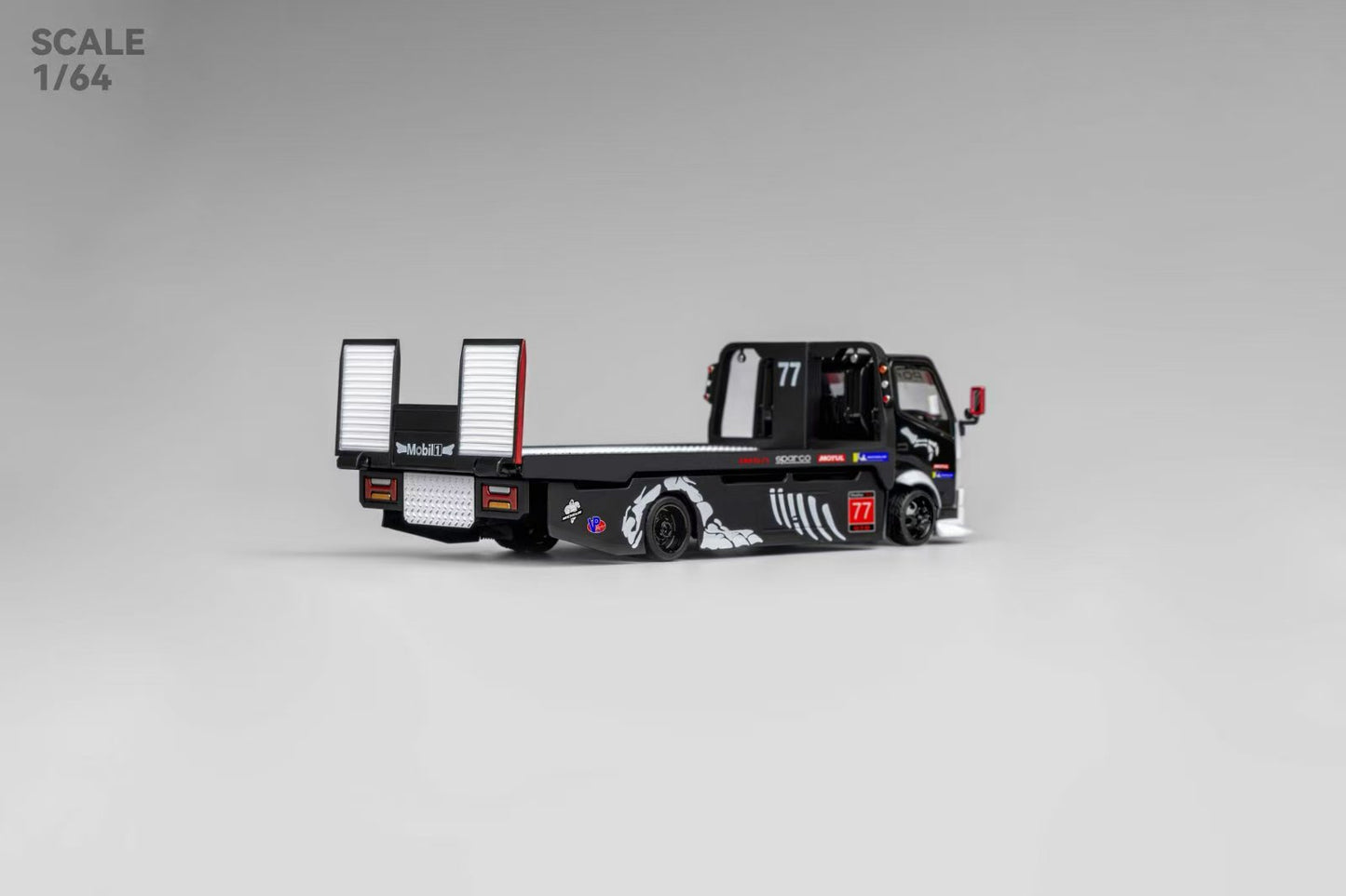 Miniature black flatbed truck model on a gray background, detailed with white graphics and number 77. Scale 1/64. Sleek and modern design.