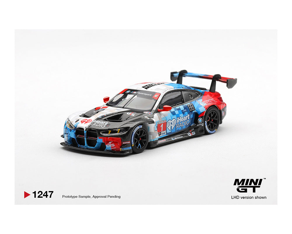 Diecast model of a BMW M4 GT3 with iHeartRadio branding and red, white, blue camouflage design on a white background.