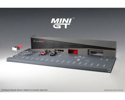 A 1:64 scale diorama of Nissan Motorsports Nismo Operation, featuring a grey structure with racing car figures on a grey surface.